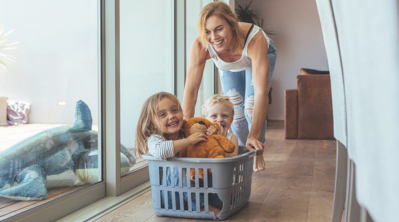 Mother pushing smiling kids in a laundry basket before emergency dentistry
