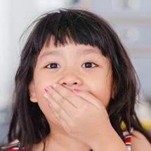 Child with lost filling covering her mouth