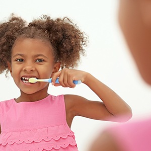 Little girl in pink shirt brushing her teeth